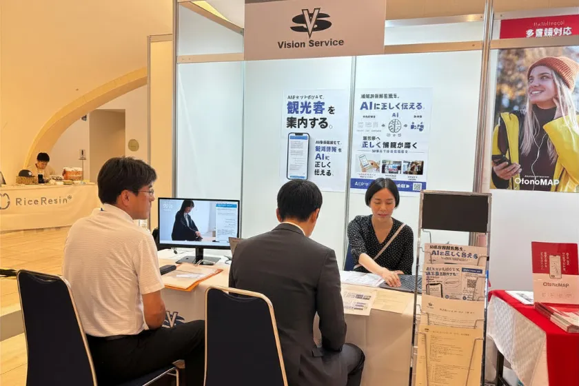 来場者へAIチャットボットやAI検索最適化について説明するビジョンサービススタッフ